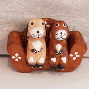 2 hand painted wooden dogs sat on a sofa