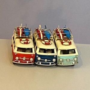 Small tin replicas of a classic VW campervan in light blue, red and dark blue.